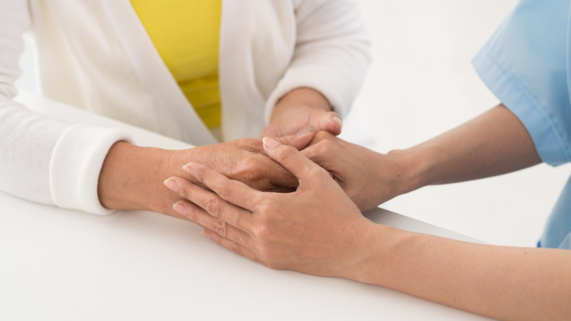 A nurse holding a woman&#039;s hand in a caring way
