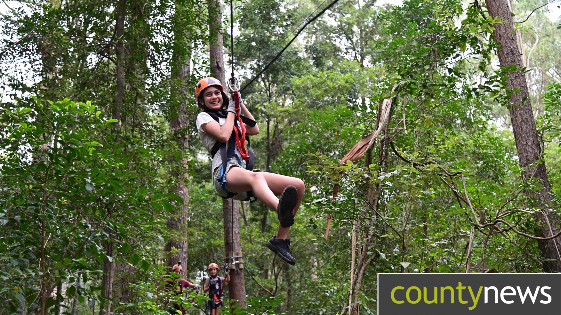 A woman zip lines through the woods