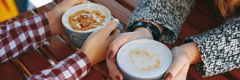 Image of women hands with freckles holding cups of coffee