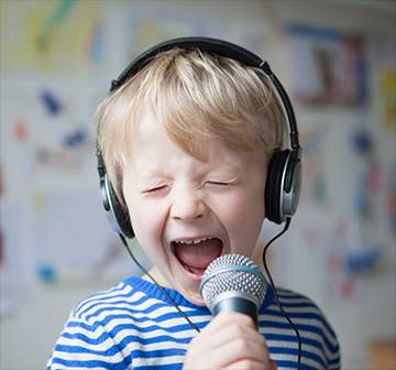 A child wearing headphones and singing into a microphone