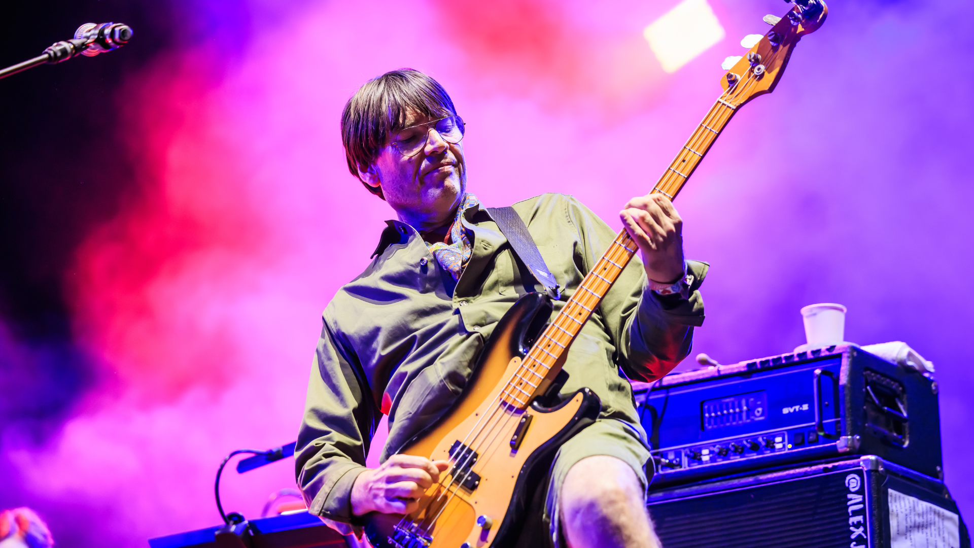 Photograph shows Alex James playing a bass guitar on stage