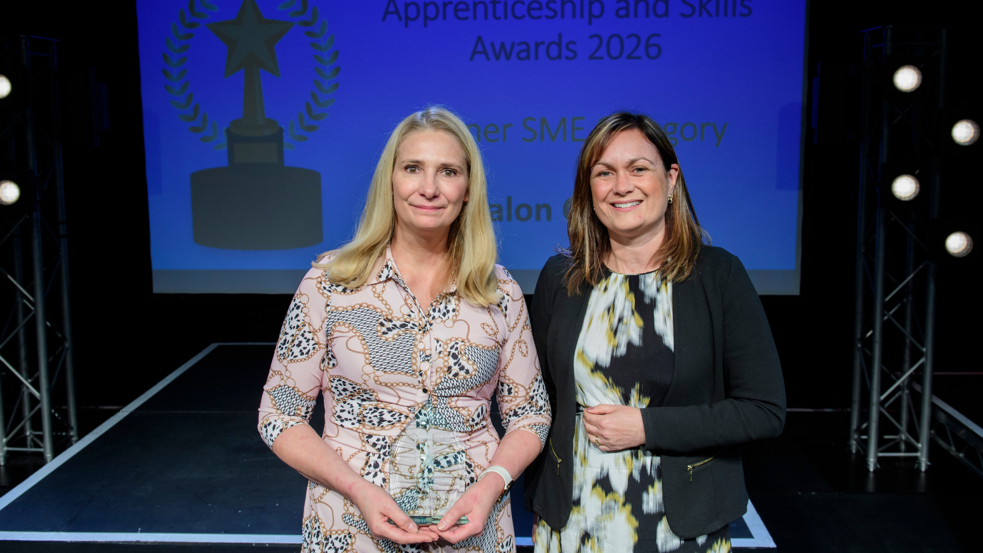Two women on stage posing with award