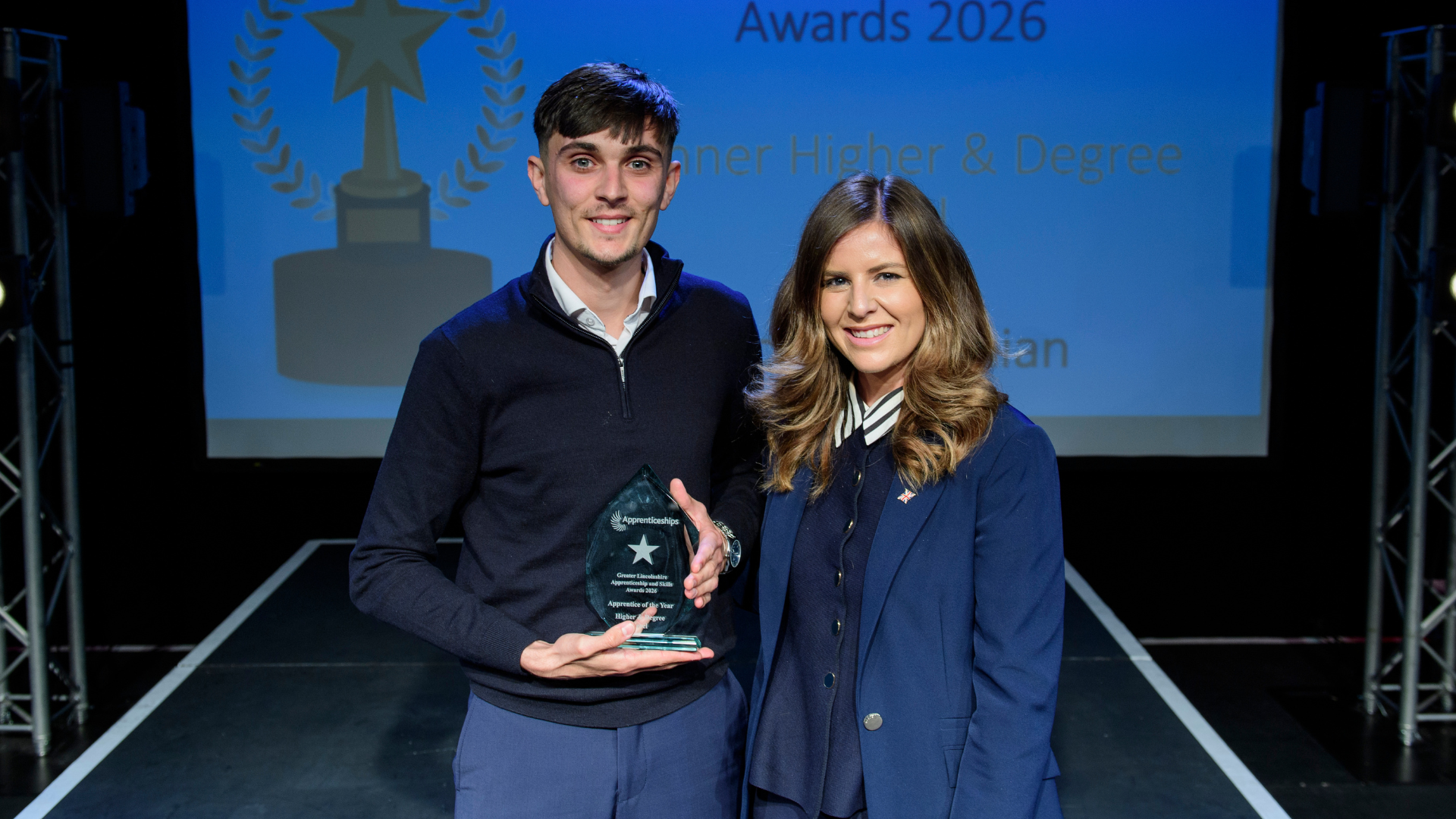 Man and woman on stage posing with award