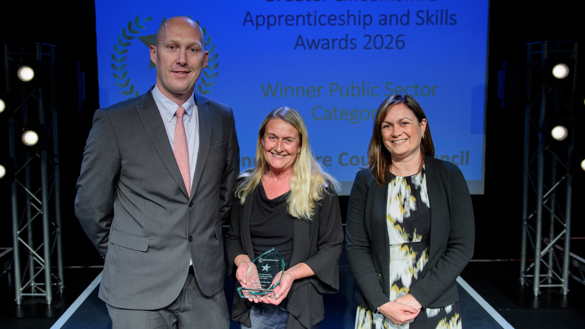 Man and two women posing with award
