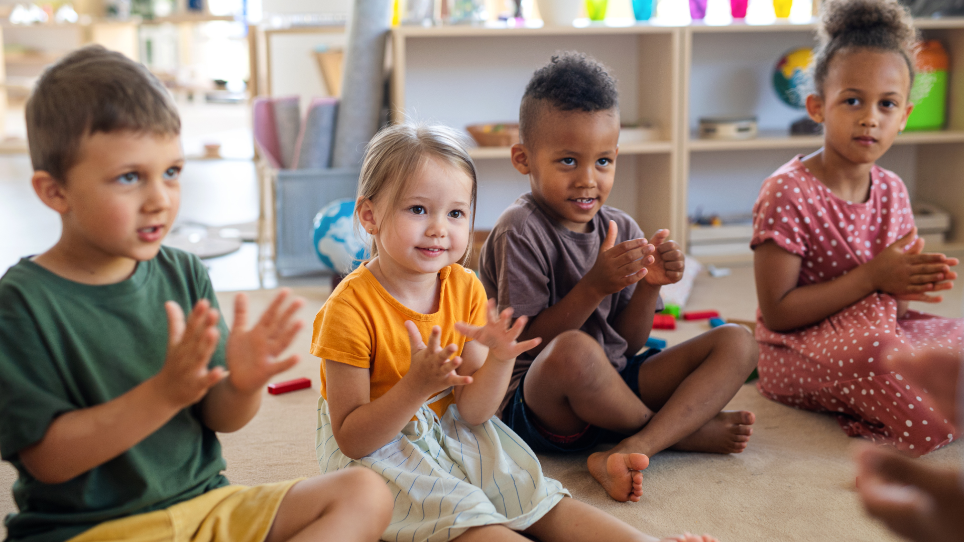 Young children sitting on the floor clapping