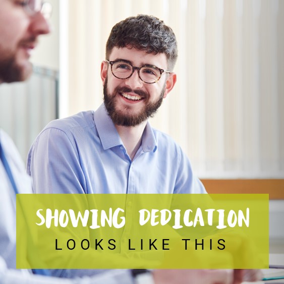 A man smiling with text reading &#039;showing dedication looks like this&#039;