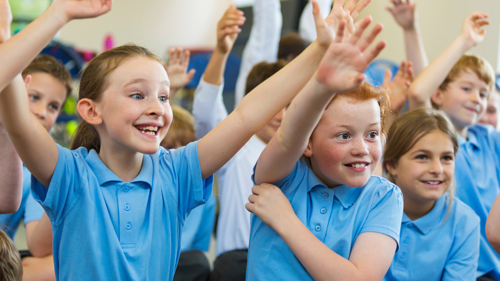 School children smiling in uniform with their hands in the air