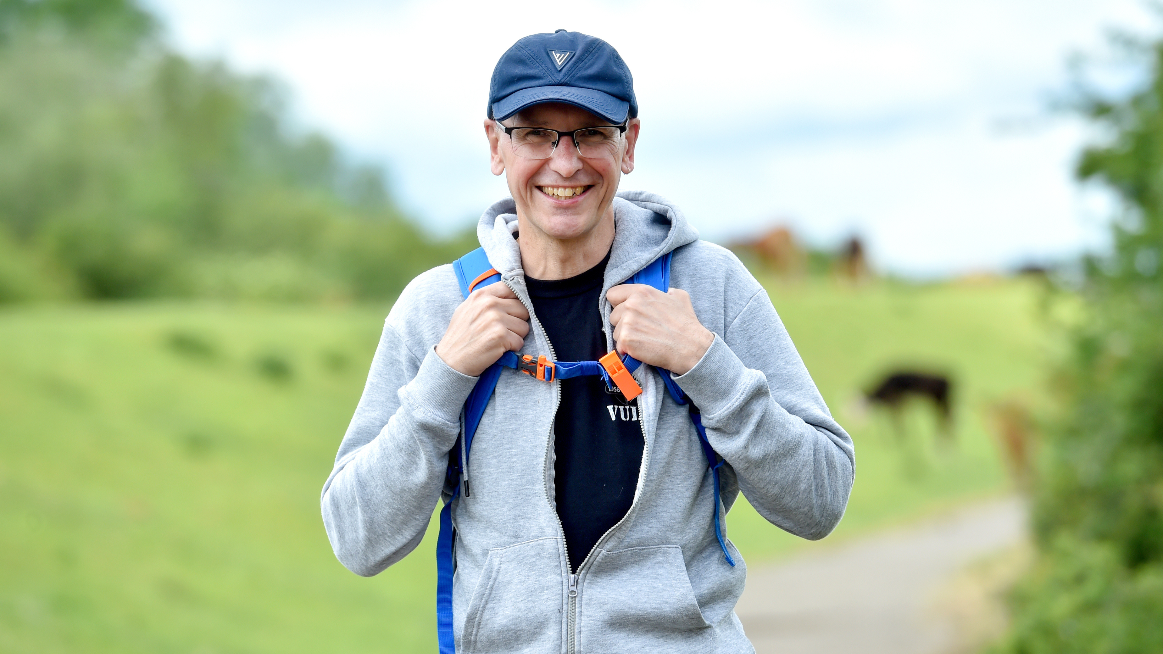 Ro Barltrop standing in the open countryside smiling with a backpack on.
