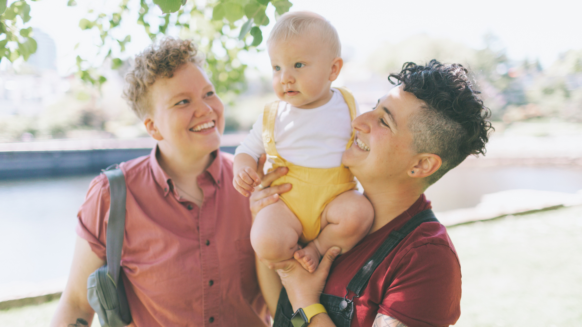 Two women holding a baby on their shoulders between them