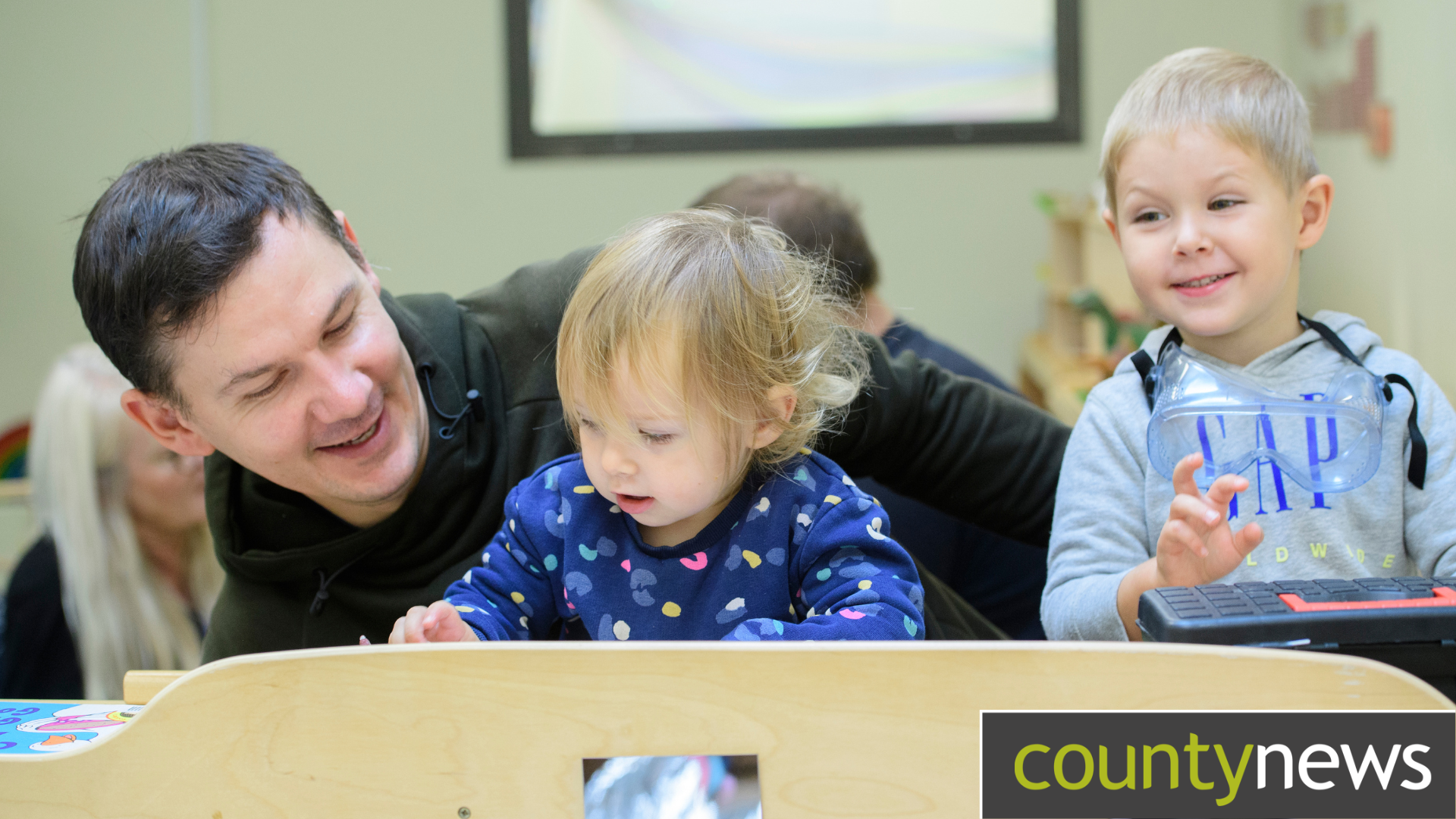 A young boy and girl making crafts with their dad in a Children's Centre
