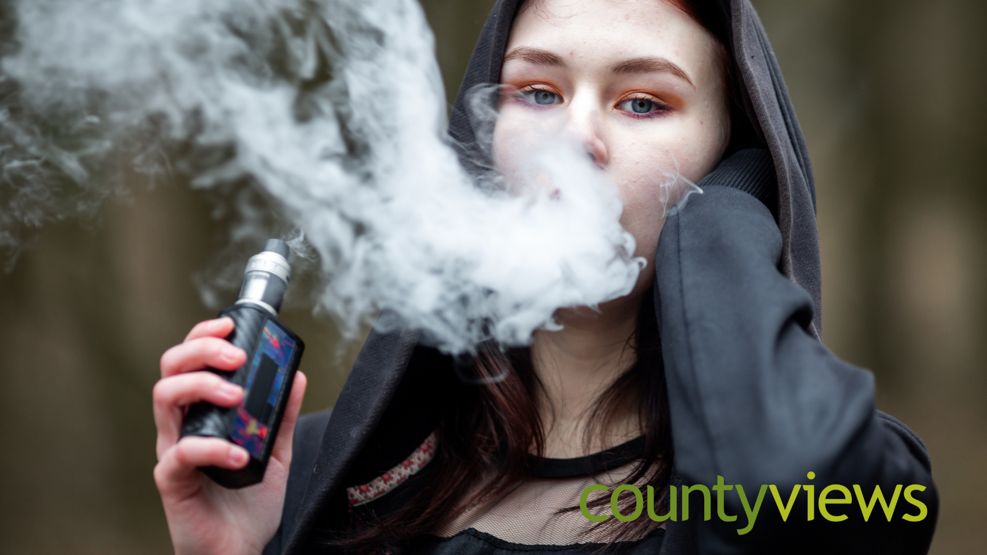 A woman with her hood up vaping