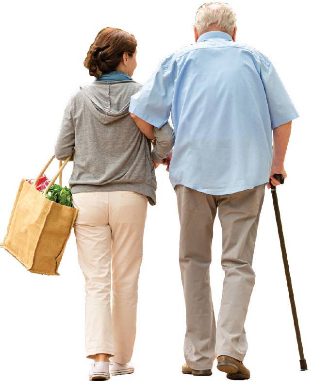 An elderly man with a walking stick walking arm in arm with a younger lady carrying shopping