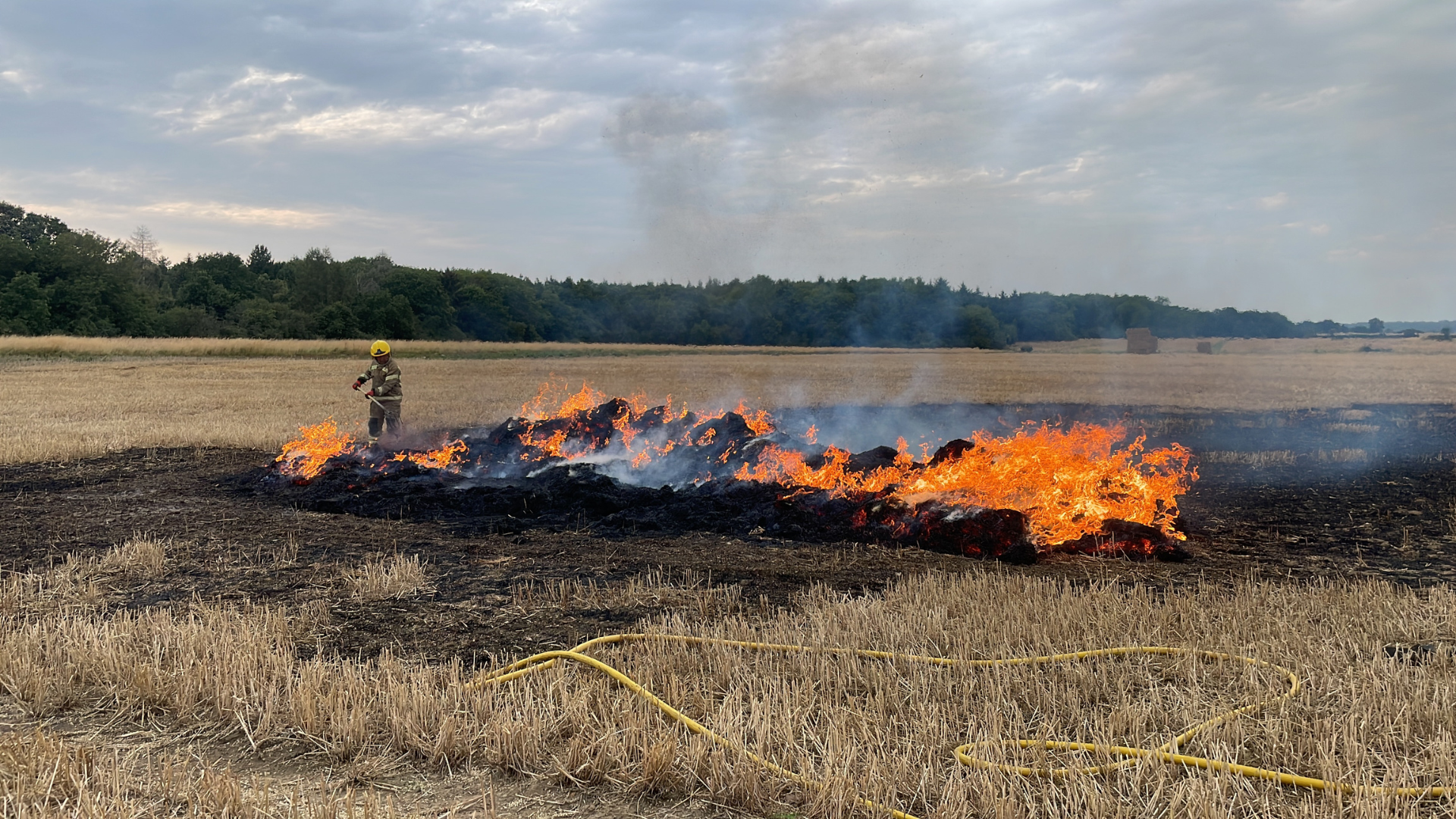 Fire on farmers field with firefighter responding