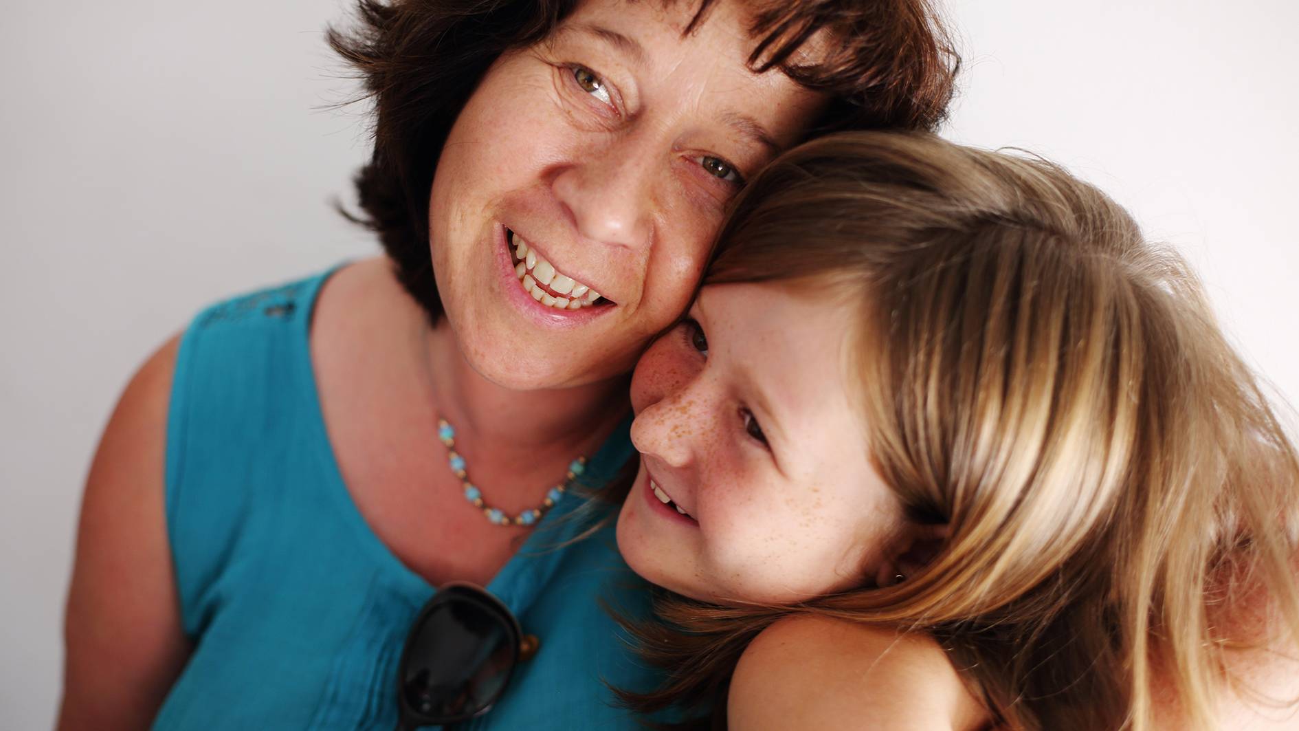 An older women smiling while cuddling a giggling young girl she is fostering.