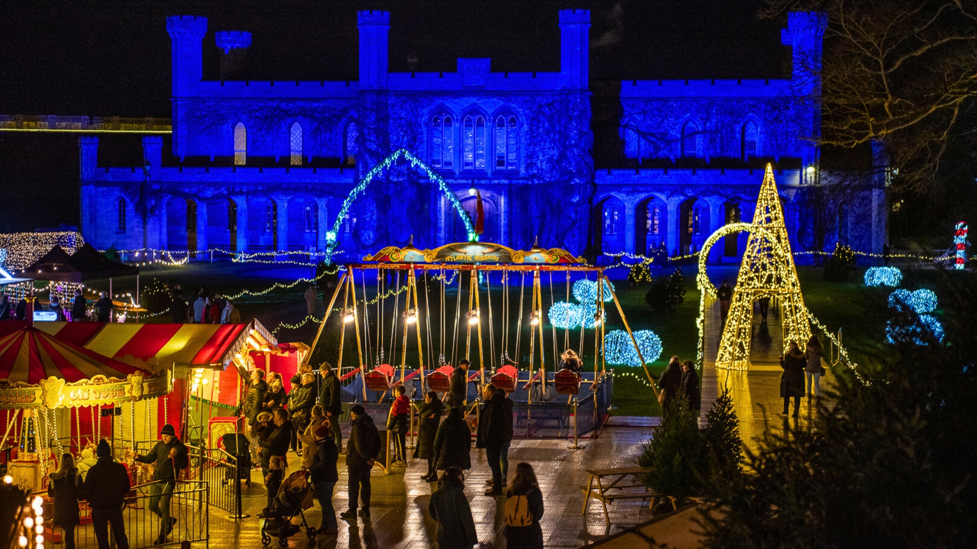 Crowds enjoying traditional fairground rides at Lincoln Castle Illuminated