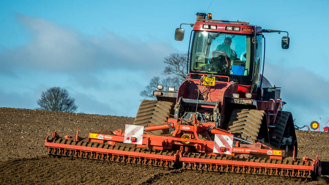 Tractor ploughing a sunny field in the county.