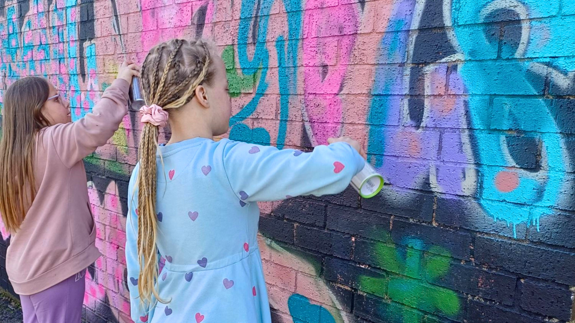 Two girls spray painting a wall at Louth Youth Centre during the Beyond project