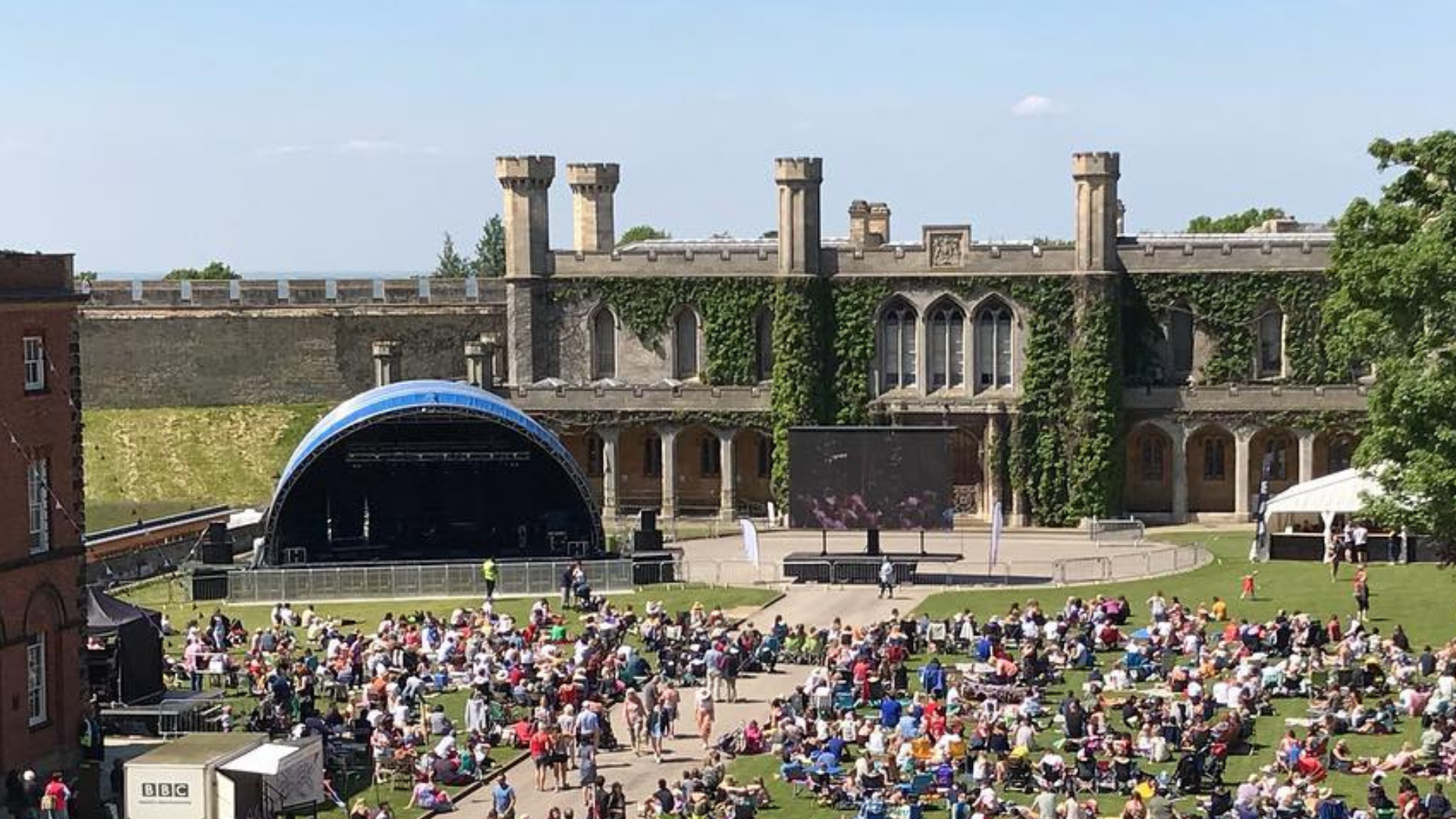 crowds sat in a historic setting facing a stage.