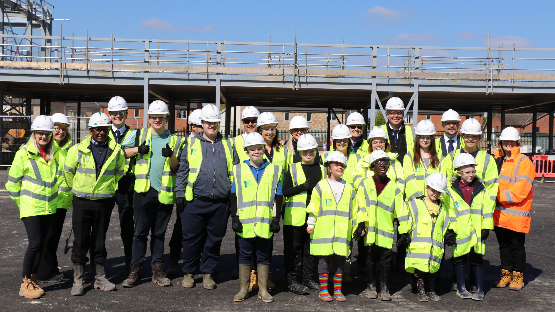 a group of people stand in front of the future site of the school