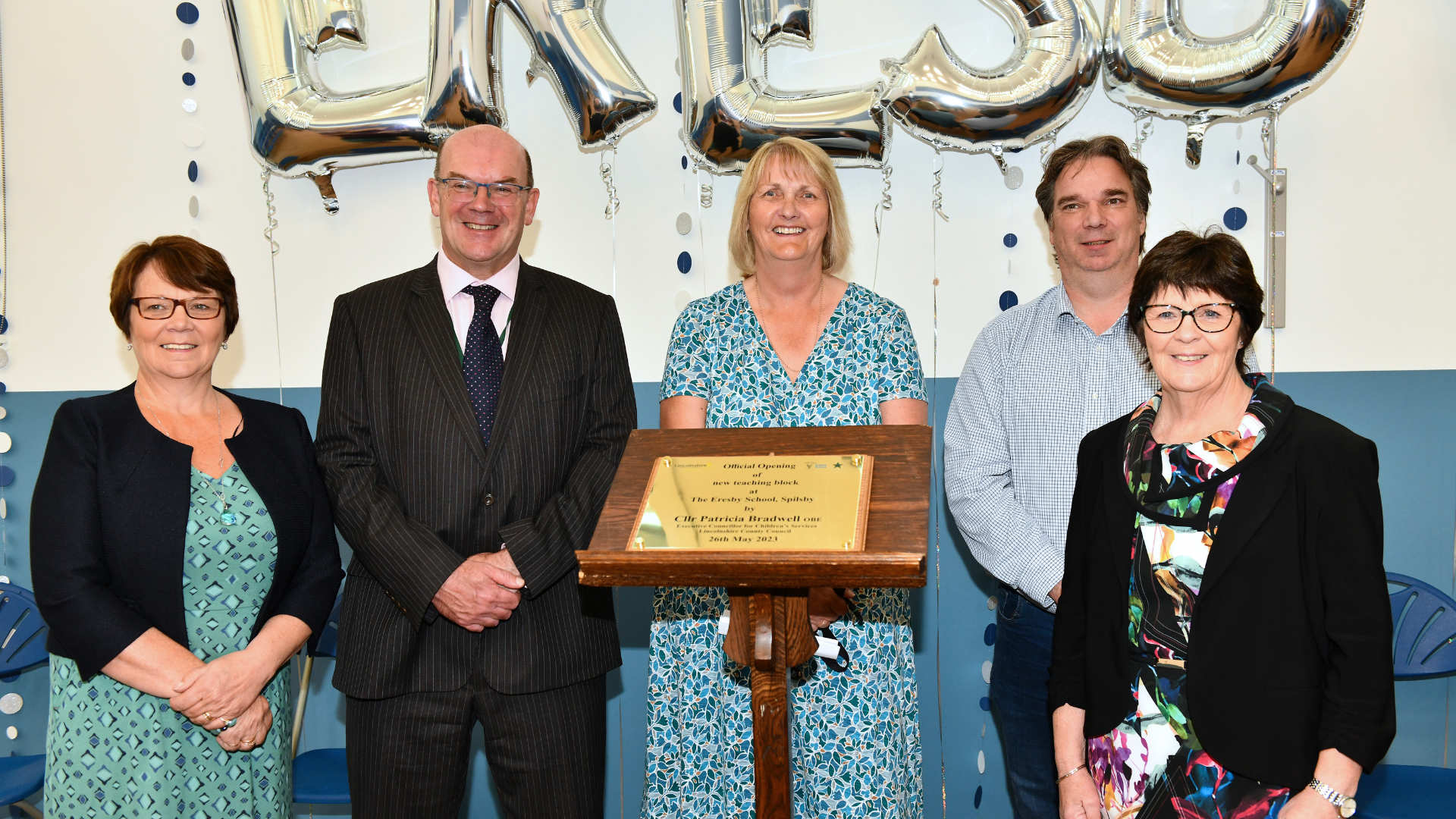 People stood in front of a lectern with an official school opening plaque