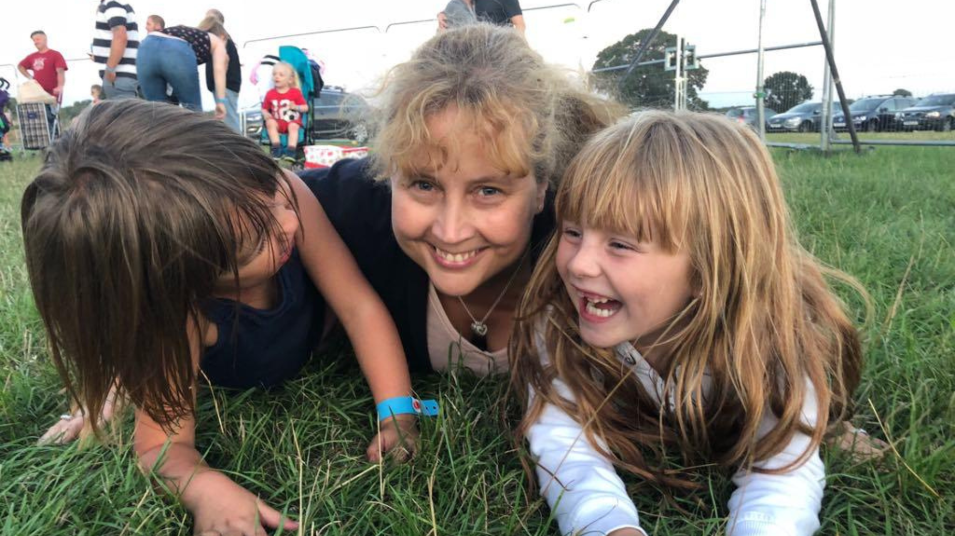 Two children and their foster carers lie in the grass laughing