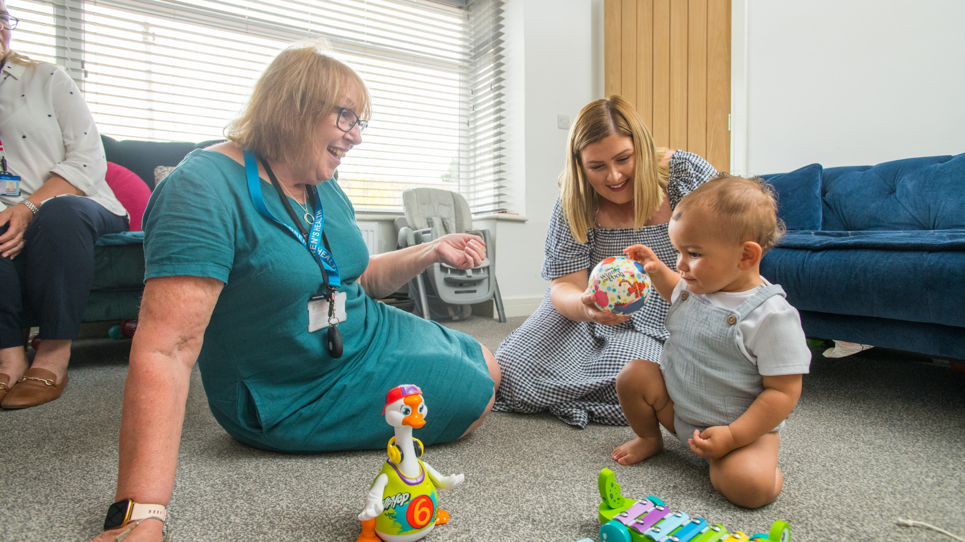 Health visitor sat with mum and child in a living room