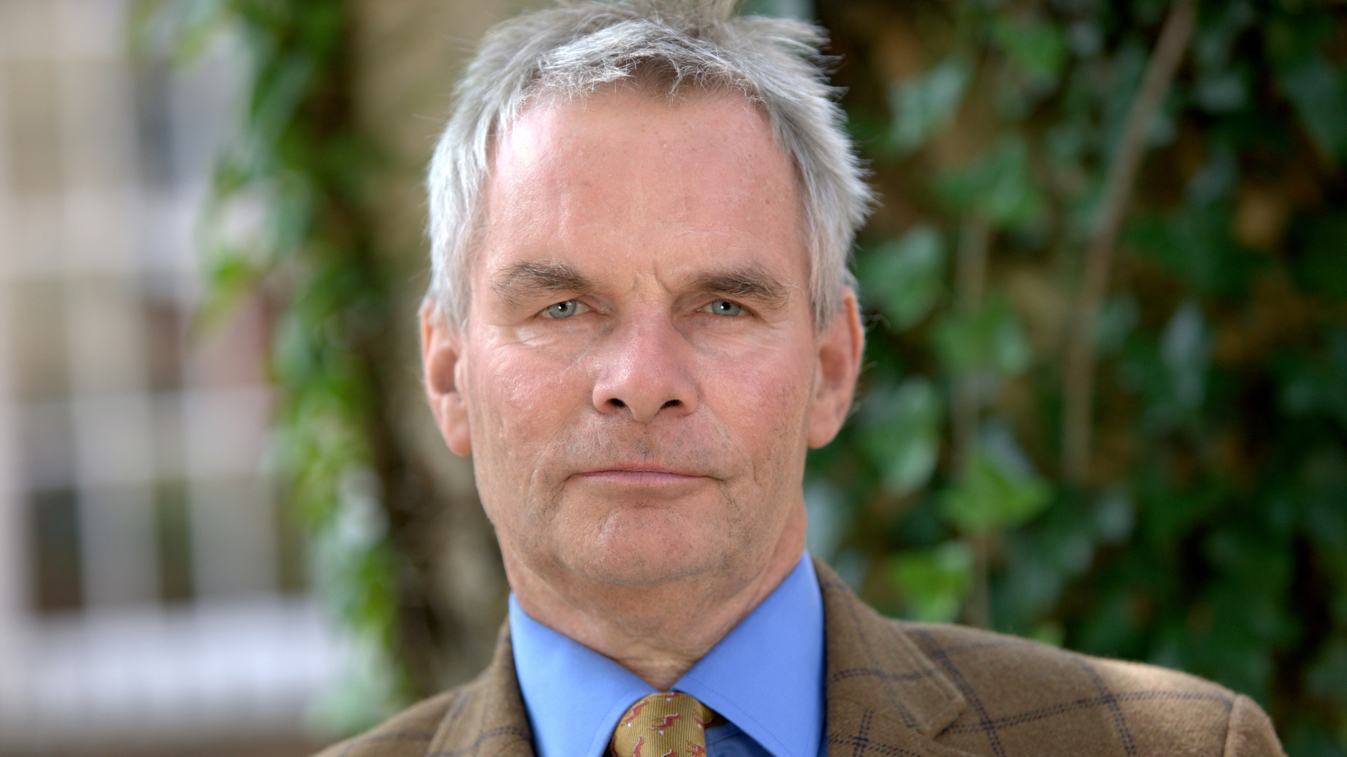 Cllr Martin Hill - a white man with grey hair wearing a blue shirt, beige tie and jacket.