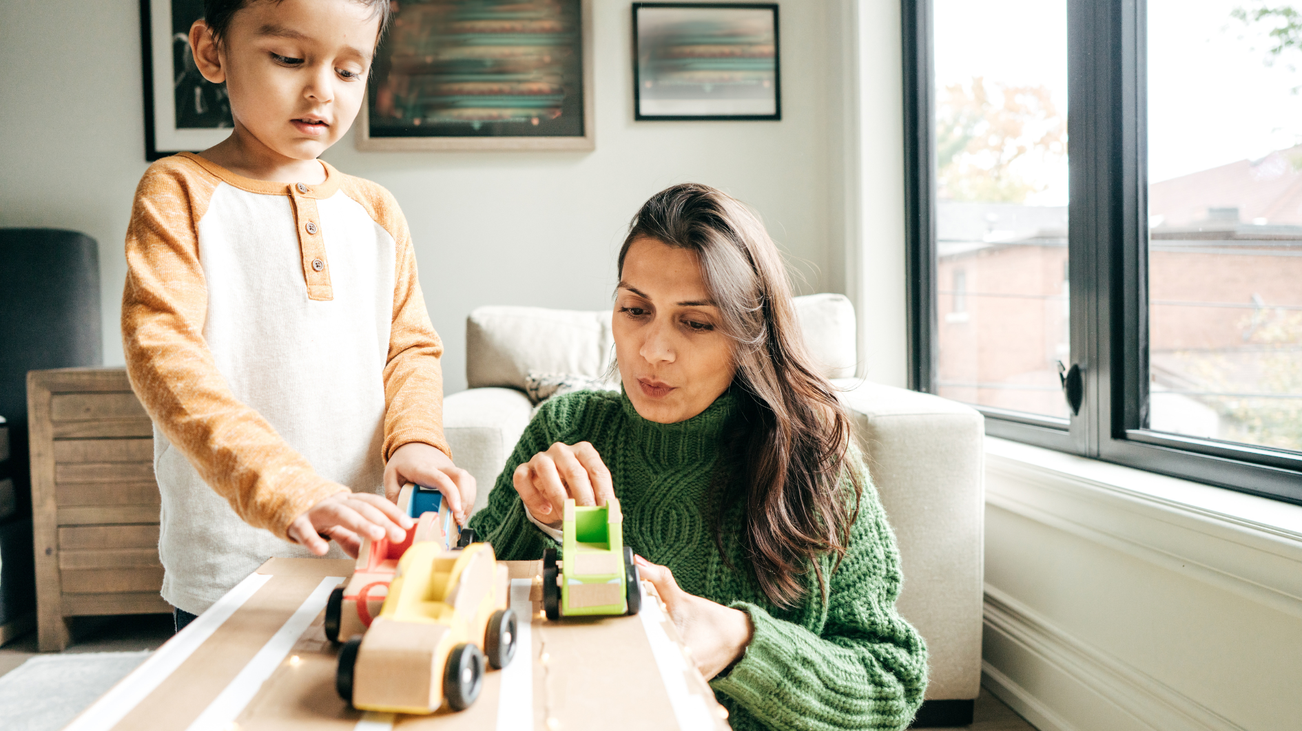 Mother and young daughter playing with toys on a coffee table in a living room