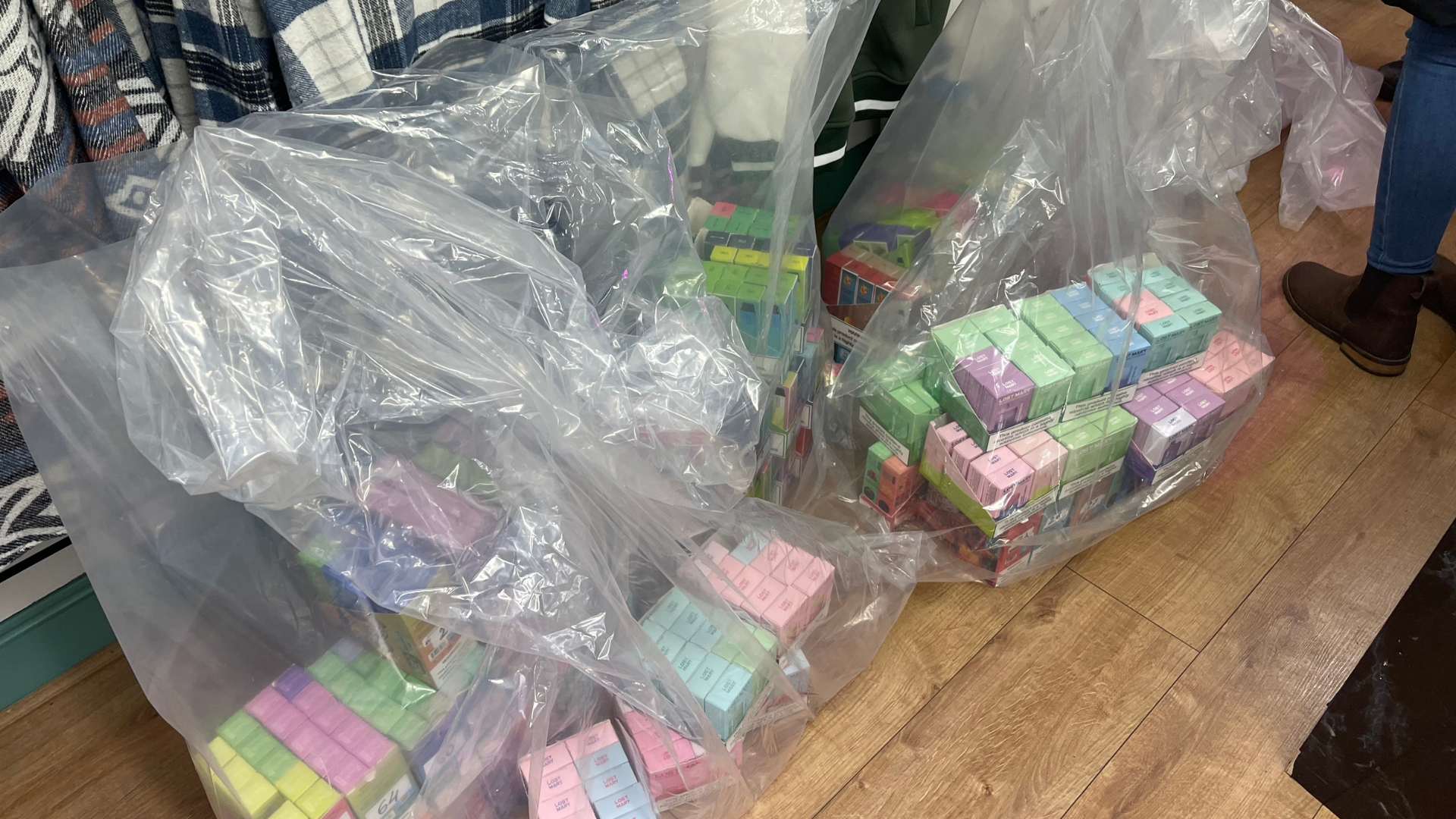 Bags of vapes in packaging bagged on a wooden shop floor.