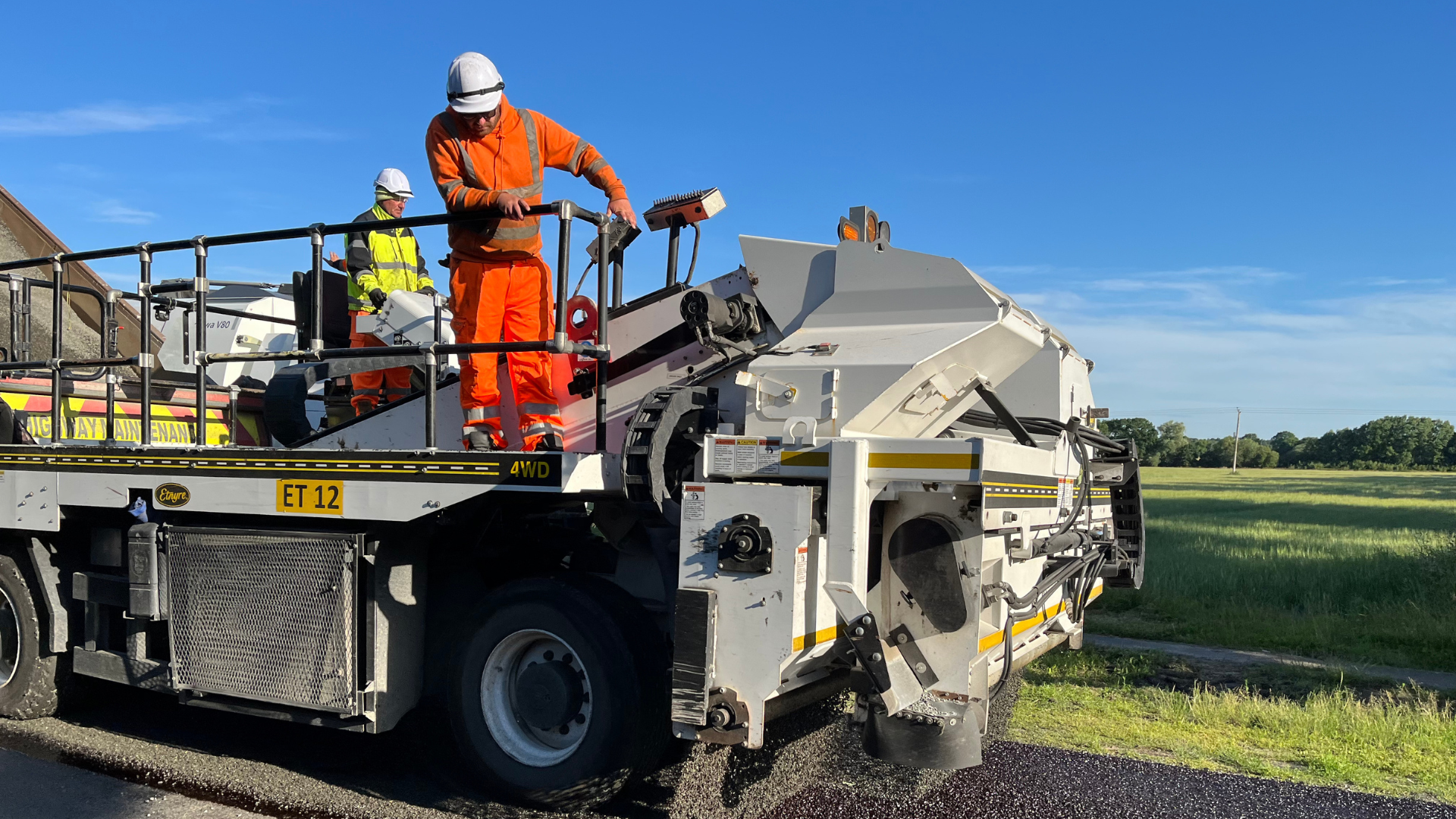 A man wearing PPE driving a highway maintenance vehicle