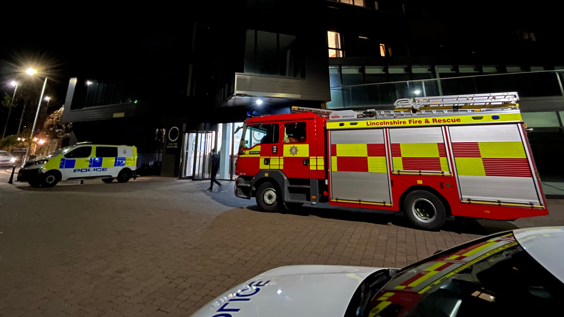 A fire engine and two police vehicles outside an apartment block called One The Brayford