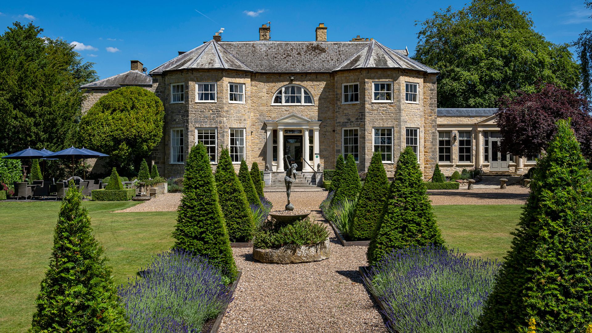 An old grand house, with a long walkway leading to the entrance.