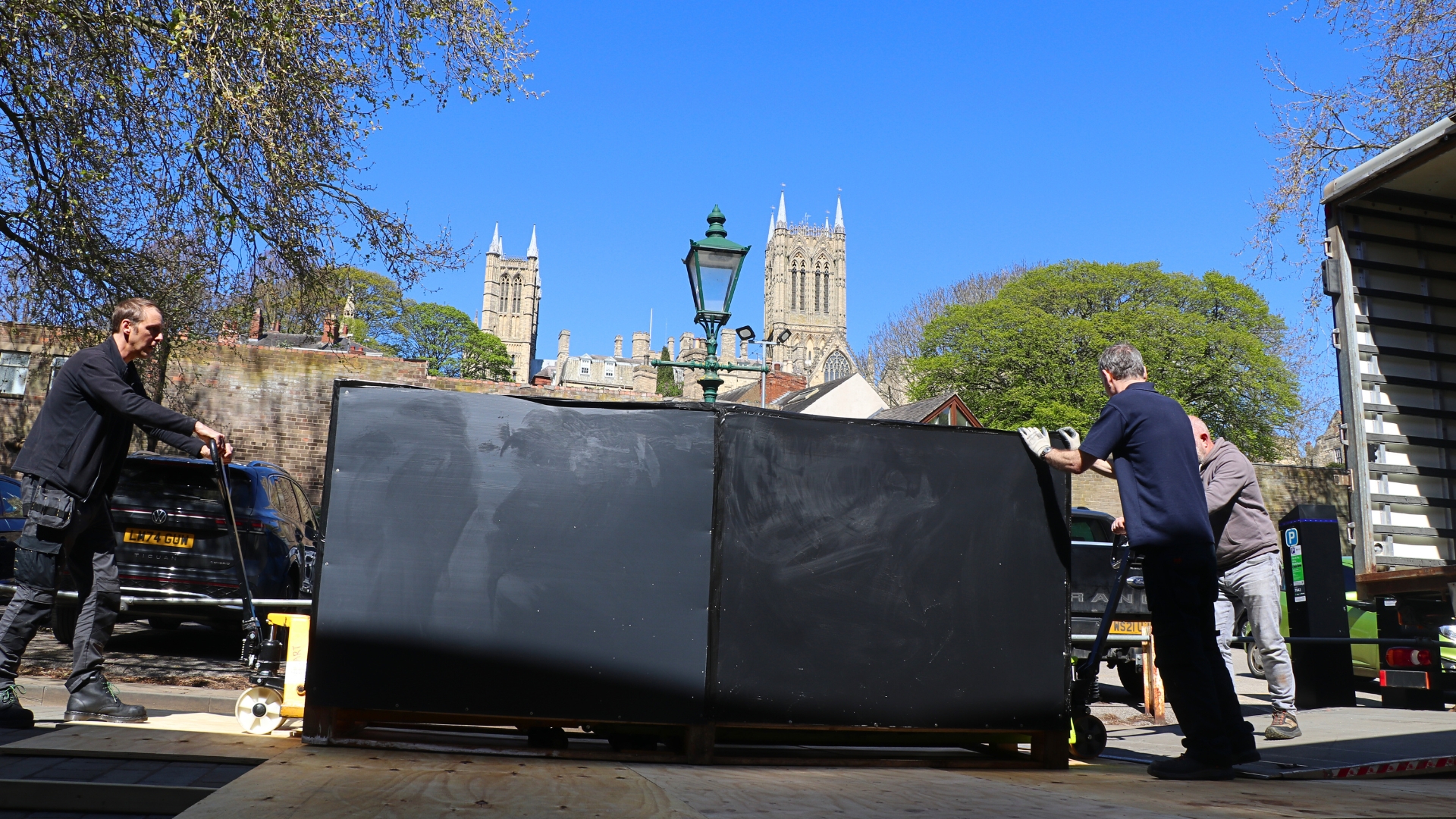 Three men unload the Tetney Coffin outside Lincoln Museum. Lincoln Cathedral is pictured in the background