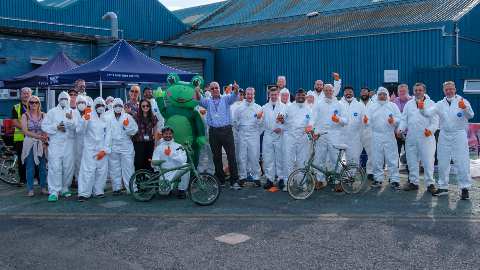 Group of people in white jumpsuits with two green bikes
