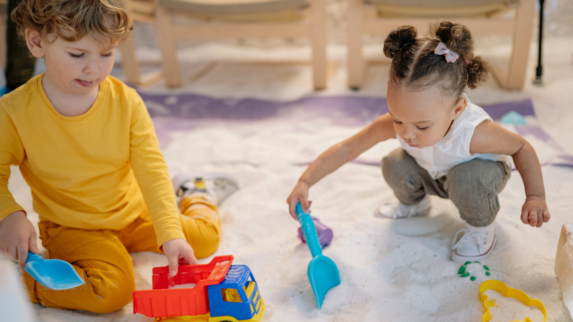 Two young children playing and digging in the sand