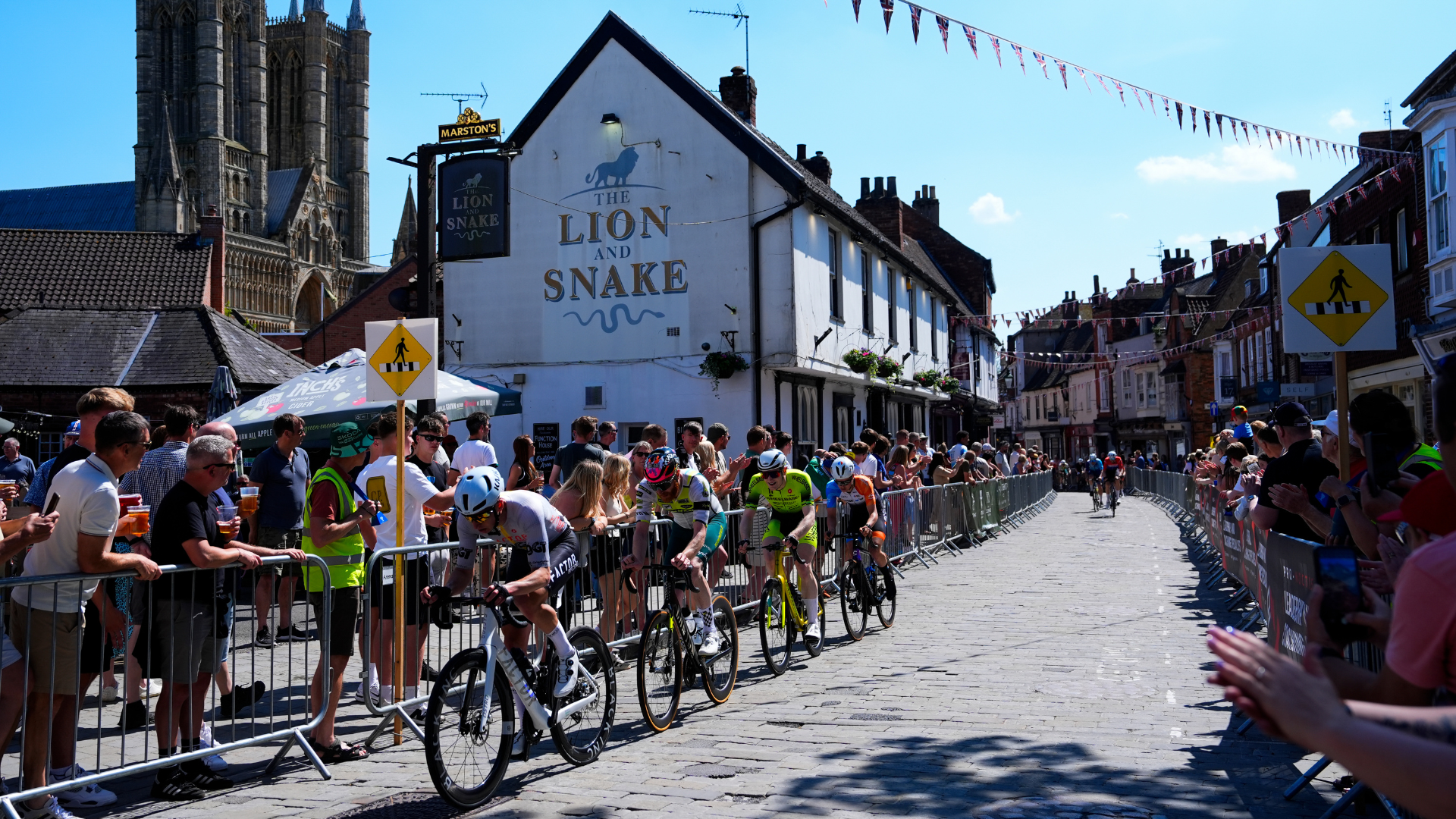 Cyclists ride down Bailgate in Lincoln with Lincoln Cathedral in the background
