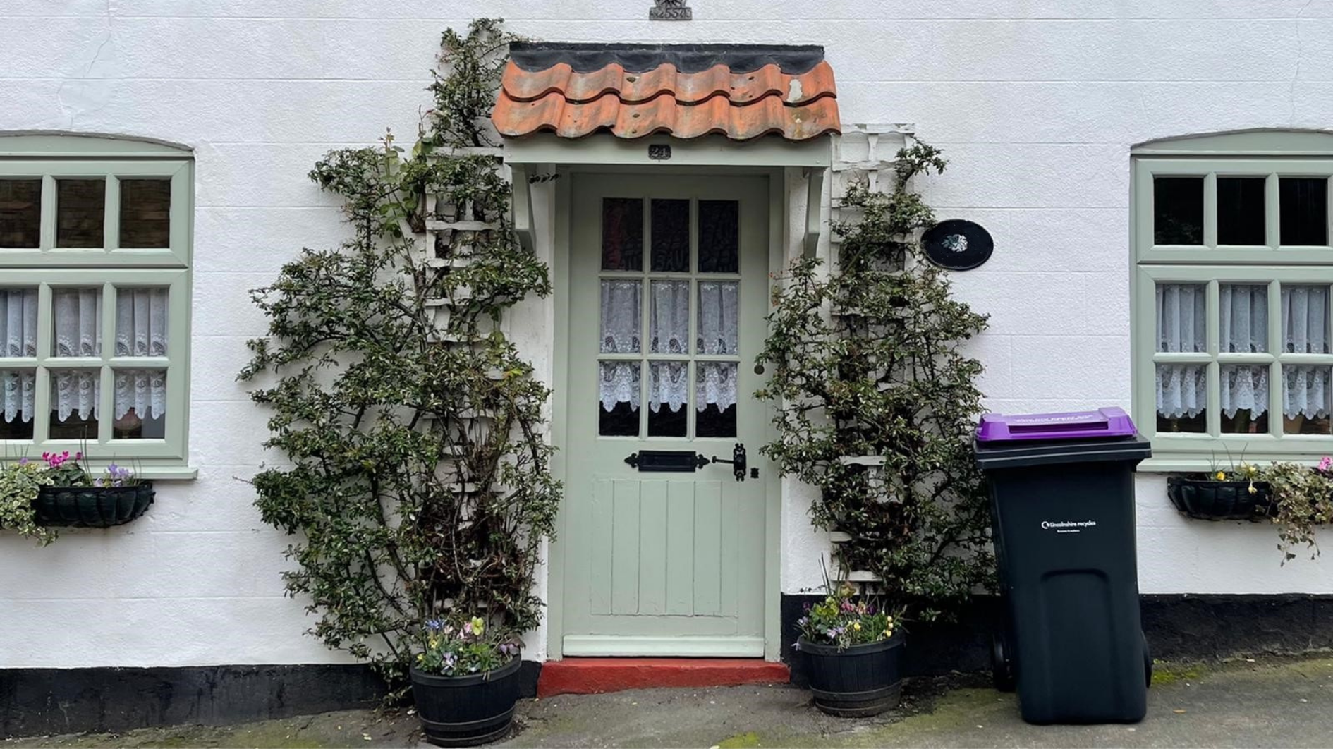 A purple-lidded bin outside a house.