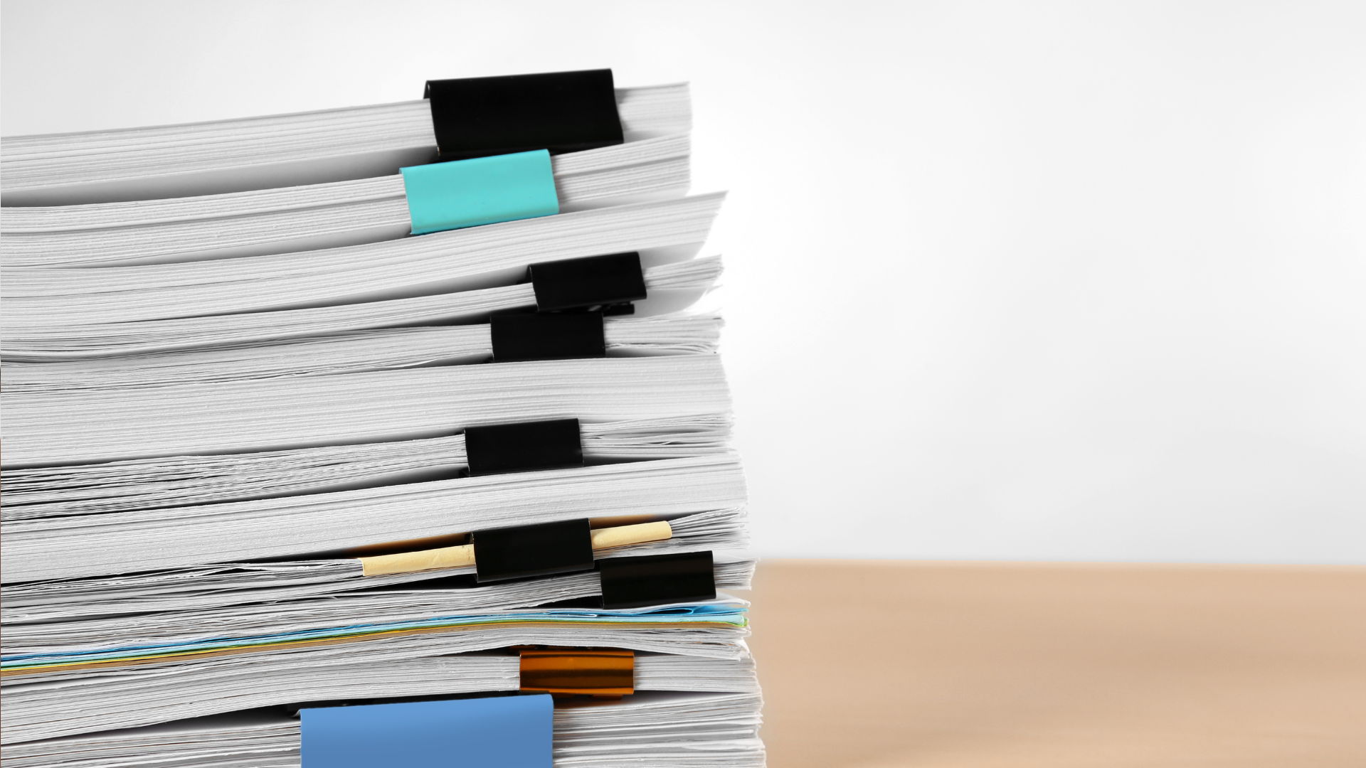 A pile of paper reports, each one clipped together