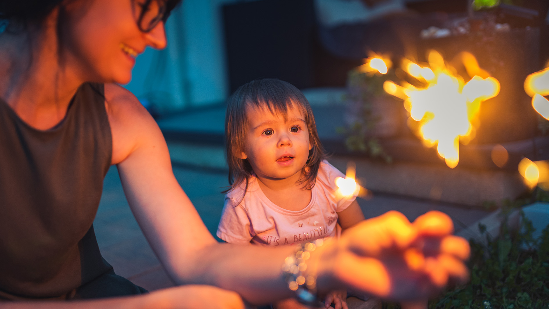 Child seeing sparkler fireworks first time outside