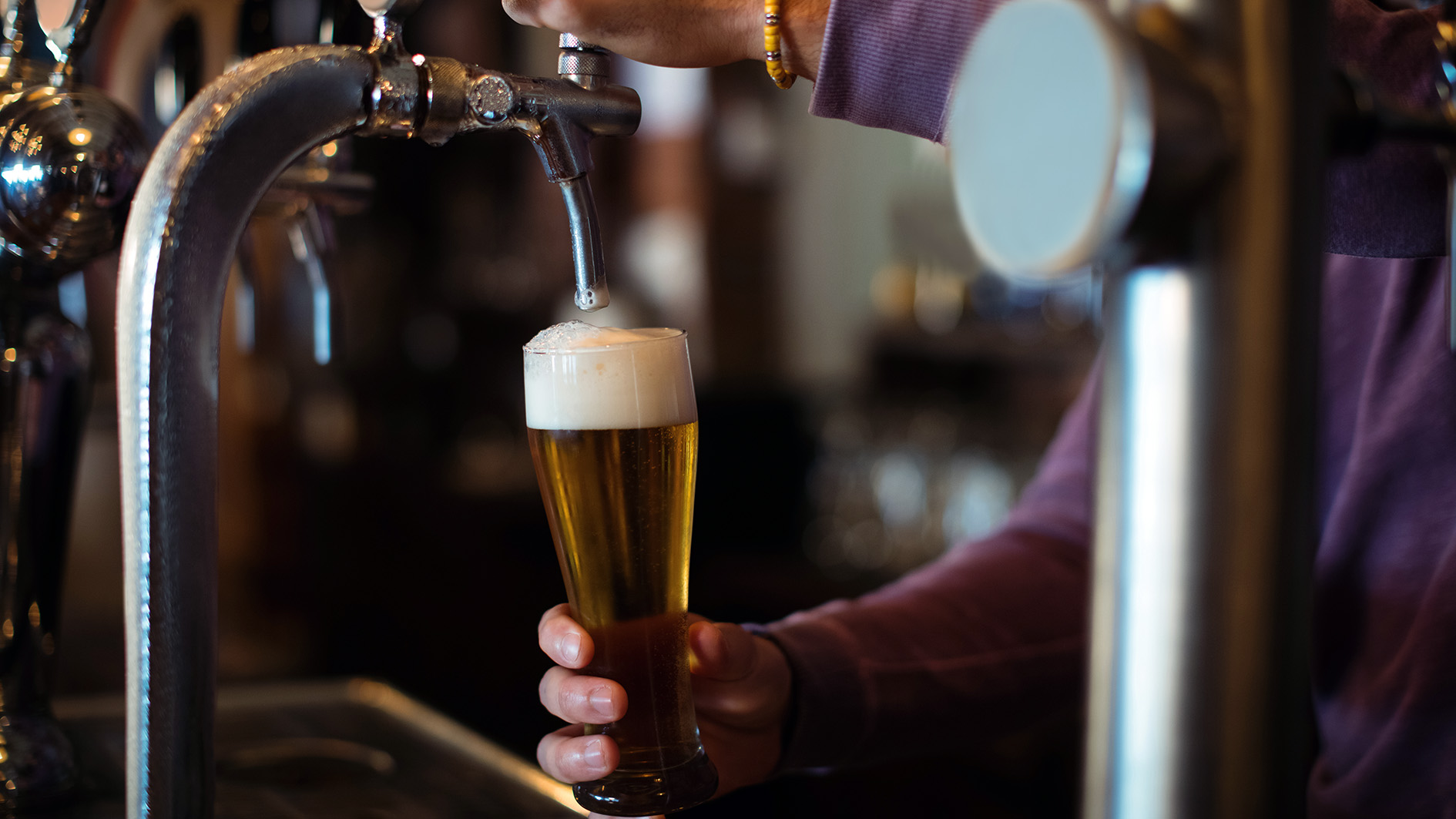 Close up of bar tender filling beer from bar pump