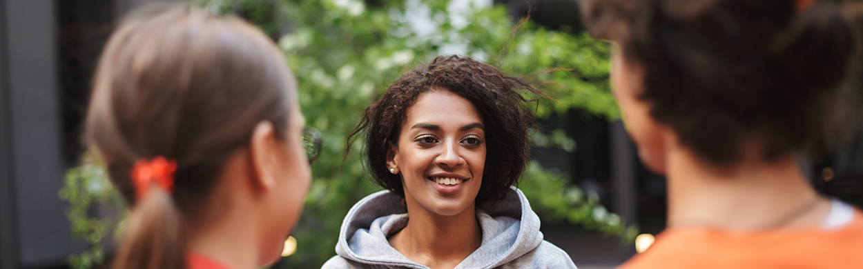 Lady with dark curly hair standing and happily talking