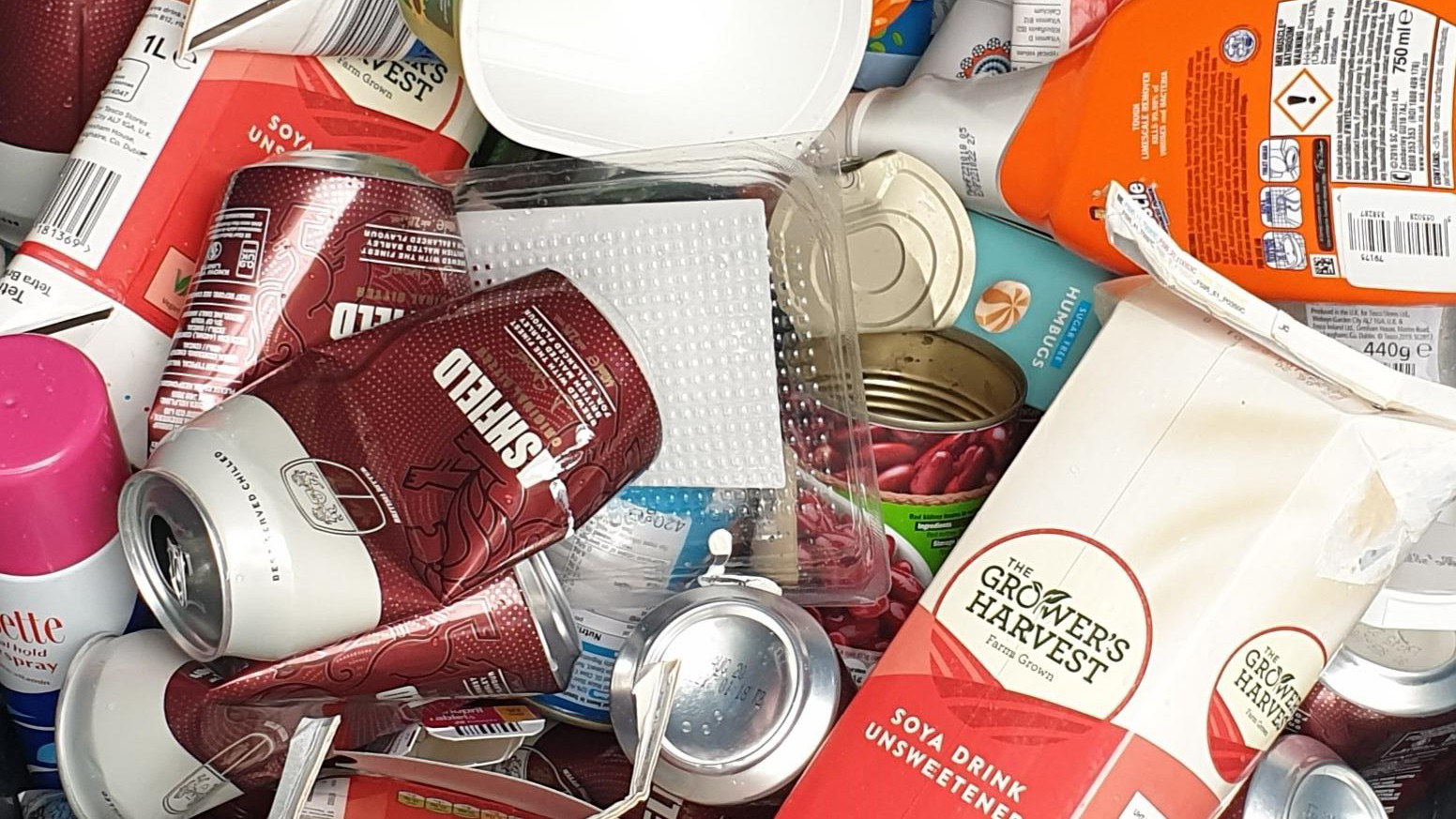 A pile of recyclable materials, such as cartons, tins, cans and white plastic tubs.
